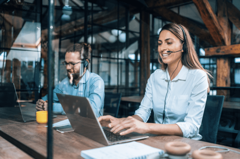 Two individuals collaborating on laptops in a small business IT support office.
