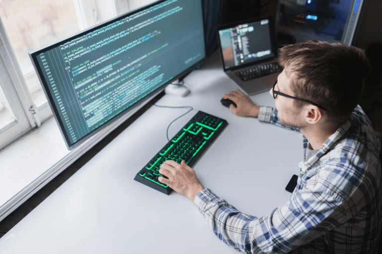 A man sits at a desk with a computer and keyboard, focused on remote work, representing the importance of cybersecurity measures for remote workers.